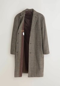 Garšs brūns un bēšs šaha raksta mētelis ar tumši brūnu iekšējo oderi, atvērta priekšpuse un garas piedurknes, kas karājas pret gaismu fona.