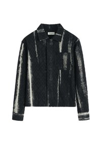 Veste à carreaux noir et blanc avec une finition texturée, devant à boutons, et une poche poitrine. Comprend un col pointu et des manches longues.