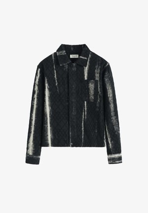 Veste à carreaux noir et blanc avec une finition texturée, devant à boutons, et une poche poitrine. Comprend un col pointu et des manches longues.