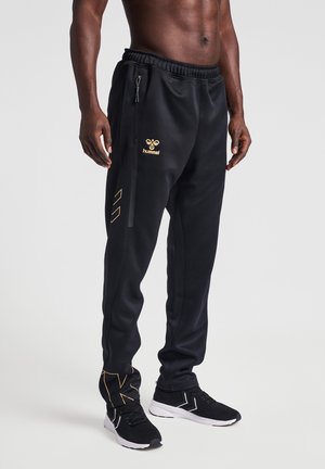 Schwarze sportliche Jogginghosen mit Kordelzugbund, ausgestattet mit einem goldenen Logo und Akzenten, Reißverschlüssen an den Taschen und tailliertem BeinDesign.