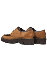 Bruine suède schoenen met een dikke, robuuste bruine zool, ronde veters en een glad leren accent op de tong voor extra detail.