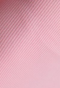 Texture de tissu rose avec nervures verticales ; surface lisse, matériau doux et léger éclat visible dans les motifs linéaires.