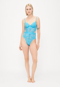 Lace bodysuit in bright blue featuring a structured cup design, adjustable straps, and cut-out detailing at the waist. Smooth texture.