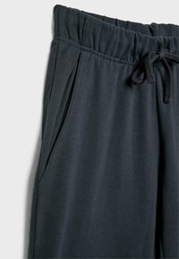 Donkergrijze sweatpants met een elastische tailleband, trekkoord, zijzakken en een zachte, gladde textuur.