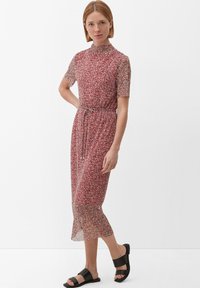 Vestido midi de estampado floral rojo con cuello alto, mangas cortas, cintura ajustada y tela transparente. Combinado con sandalias negras de estilo deslizante.