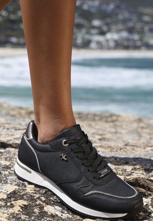 Schwarze Sneaker aus strukturiertem Material, weiße Sohle und metallische Akzente. Verfügt über ein Schnürdesign und ein Logoschild an der Seite.