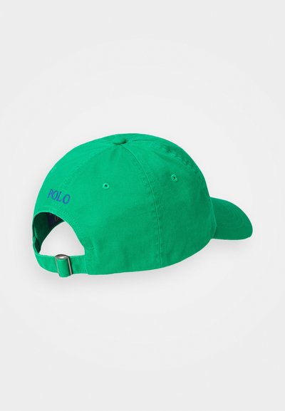 Boné de beisebol verde em algodão com uma aba curva, faixa ajustável na parte de trás e "POLO" bordado em roxo na lateral.
