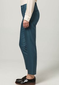 Teal op maat gemaakte broeken met een slim fit, platte voorkant en een gladde textuur. Gecombineerd met zwarte glanzende schoenen met veters.