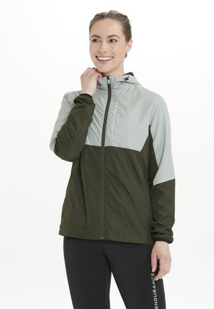 Letvægts zip-up jakke med et to-farvet design bestående af en lys grå top og en mørk grøn bund. Inkluderer hætte og lynlåslomme.
