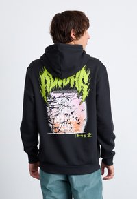 Svart hoodie med en färgglad grafisk tryck på baksidan, med gröna låga accenter och text. Mjuk fabric, avslappnad passform och kenguruficka.