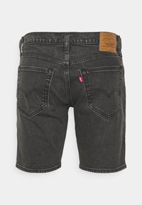 Shorts en denim noir à coupe droite, poches arrière ornées d'une couture en forme de cœur, et une étiquette en cuir marron sur la ceinture.