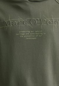 Sweat-shirt vert foncé avec texte en relief "Marc O'Polo" et un design linéaire au-dessus, accompagné d'un message sur la durabilité en dessous, texture de tissu lisse.