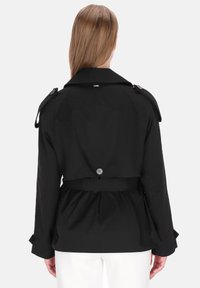 Fekete ballonkabát övvel a deréknál, széles ujjal és vállpántokkal. Simább anyag, hátul gombos záródással.