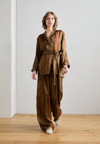 Completo a due pezzi marrone a fantasia con camicia bottonata, pantaloni a gamba larga e una cintura coordinata, realizzato in un tessuto liscio e leggero.
