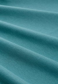 Türkisfarbener Baumwollstoff mit glatter Textur, der dezente Falten und ein einheitliches Finish aufweist und sich für verschiedene Textilanwendungen eignet.