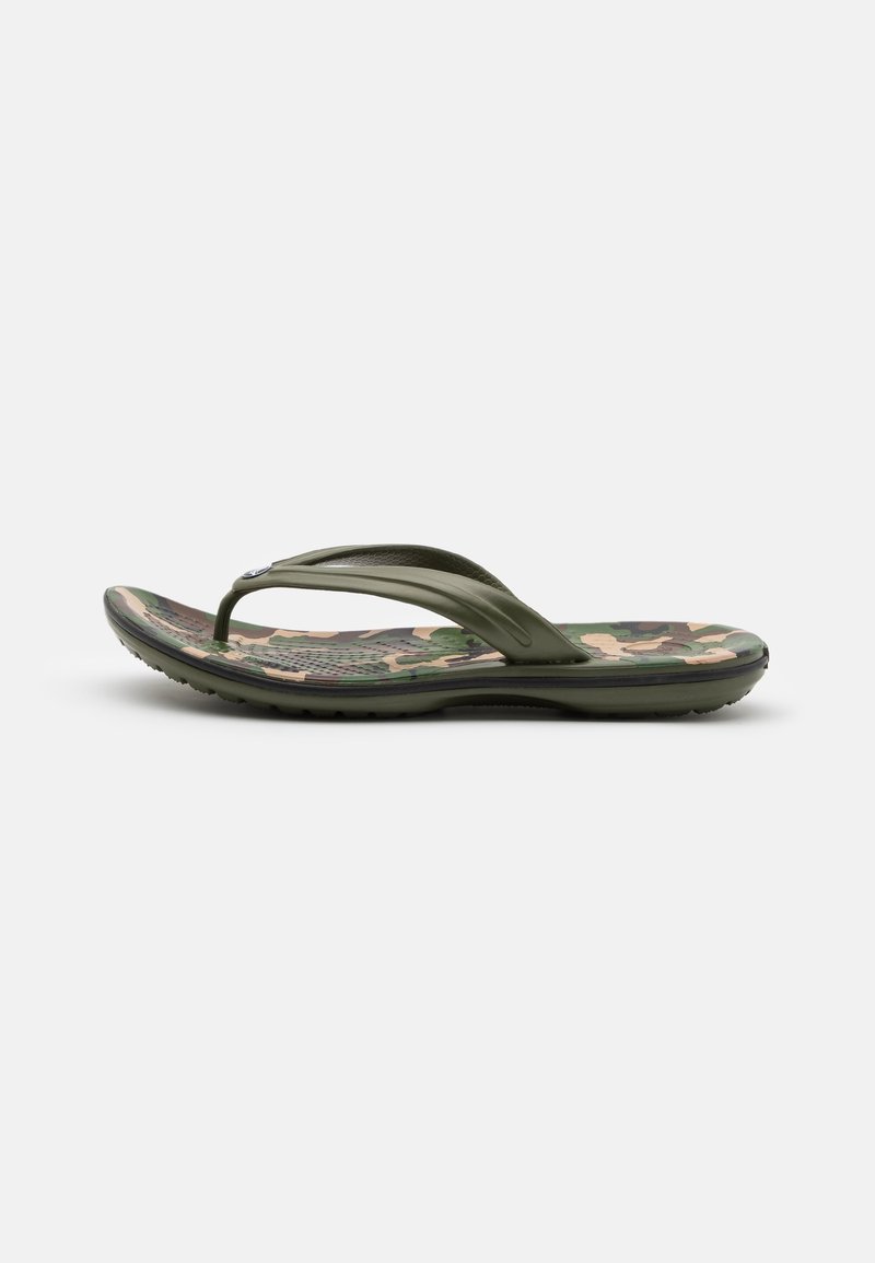 Une seule tong verte avec une semelle imprimée camouflage et des brides texturées, présentée sur un fond clair uni.