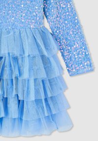 Niebieska sukienka z długimi rękawami, pokryta cekinami. Posiada warstwową spódnicę z tiulu z falbanami, co tworzy teksturę i wymiar.