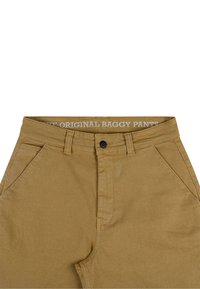 Baggy hlače od bež pamučne tkanine, s kopčanjem na dugme, koso postavljenim prednjim džepovima i strukom označenim "THE ORIGINAL BAGGY PANTS."