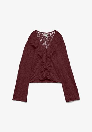 Blouse en dentelle bordeaux avec manches longues et décolleté en V froncé, motif floral texturé et longueur légèrement cropped.