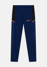 Pantalones deportivos color azul marino con paneles laterales negros, ribete naranja, cinturilla elástica, bolsillos y logo de swoosh de Nike en naranja en el muslo derecho.