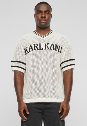 Hvid strikket kortærmet sweater med V-hals, der har et sort "KARL KANI" logo og sorte stribede detaljer på ærmerne.