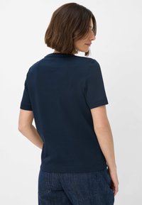 Kurzärmliges, marineblaues T-Shirt aus Baumwolle mit Rundhalsausschnitt und geradem Saum, kombiniert mit Jeans.