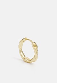 Kuldrenk, millel on ebaregulaarne, tekstureeritud disain ja veidi väänatud kuju. Siseosa on sile, samas kui välimine osa on orgaaniliste, ebaühtlaste detailidega.