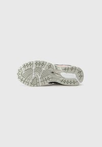 Black athletic shoe with textured gray rubber sole, featuring distinctive tread pattern and a cushioned design for impact absorption.
