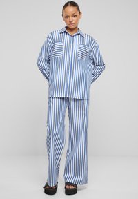 Set di pigiama a righe blu e bianche, composto da una camicia con bottoni e due tasche sul petto, e pantaloni a gamba larga, realizzato in tessuto morbido.