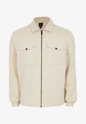 Beige zip-up jack gemaakt van zachte stof, met een puntige kraag, twee borstzakken met kleppen en aansluitende manchetten.