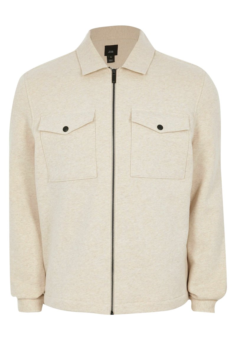 Giacca beige con zip realizzata in morbido tessuto, dotata di colletto a punta, due tasche sul petto con acqua e polsini aderenti.