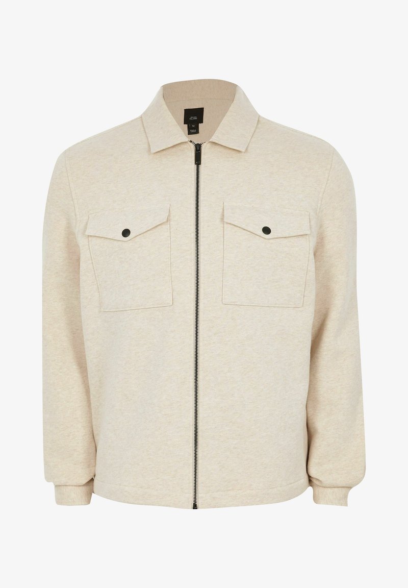 Giacca beige con zip realizzata in morbido tessuto, dotata di colletto a punta, due tasche sul petto con acqua e polsini aderenti.