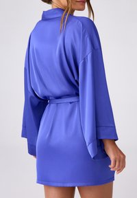 Sukienka z satyny w żywym niebieskim kolorze, z długimi rękawami, paskiem i luźnym krojem o gładkiej fakturze.