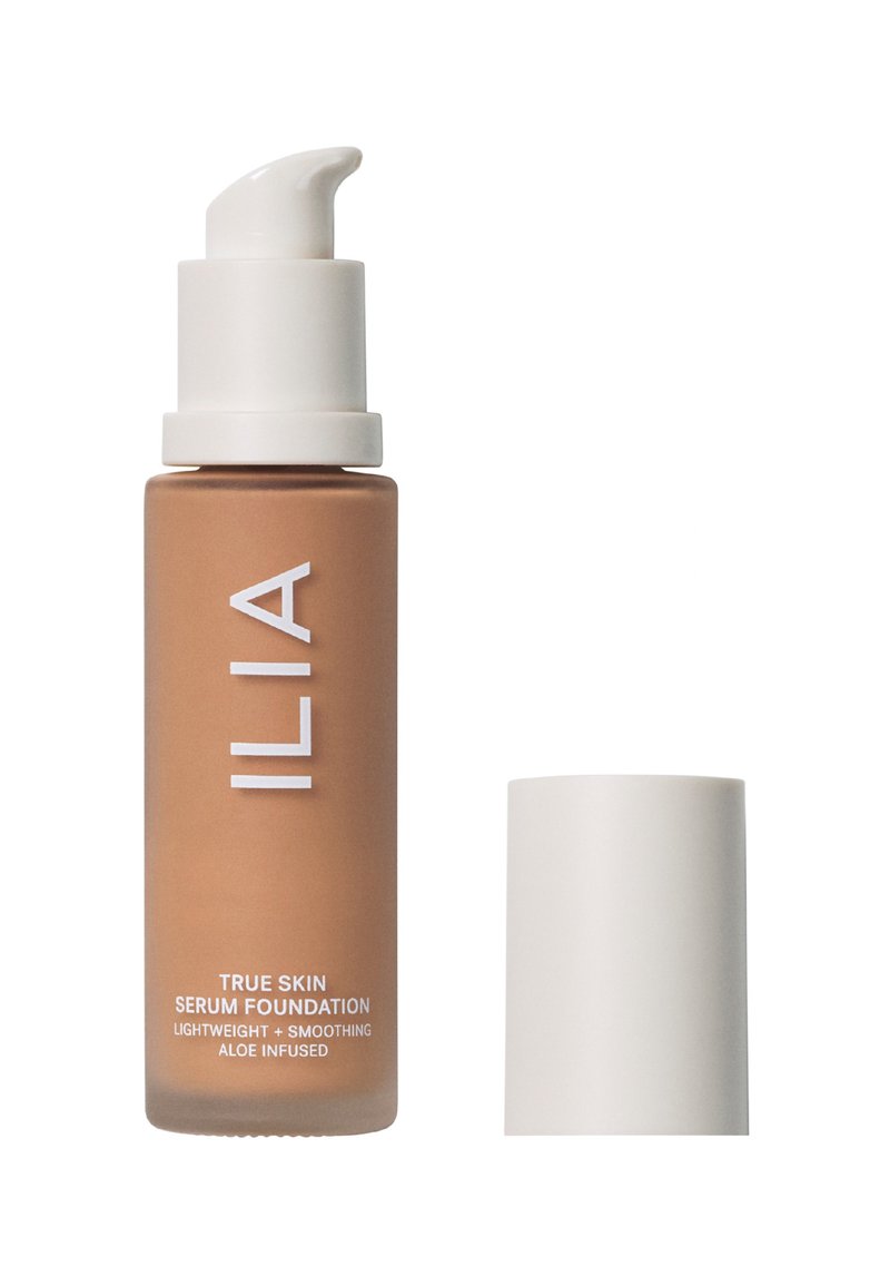 ILIA True Skin Serum Foundation i en brun glassflaske med en hvit pumpemekanisme; teksten på flasken indikerer at den er lett og beriket med aloe.