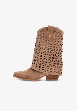 Bota de tobillo en ante color camello con patrón geométrico de recortes, lengüeta superior doblada con botón y tacón bajo de madera apilada.