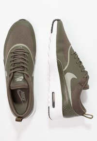 Olivově zelené tenisky Nike Air Max Thea s mesh svrškem, bílou mezipodešví, texturovanými akcenty a viditelnou vzduchovou jednotkou v patě.