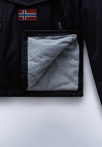 Navy jacket featuring a red and blue Norwegian flag patch; grey fleece lining visible in unzipped pocket, contrasting textures.