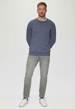 Dunkelblaues Sweatshirt mit Rundhalsausschnitt, kombiniert mit hellgrauen Jeans und weißen Sneakers. Einfaches Design, strukturierter Stoff, minimales Branding.