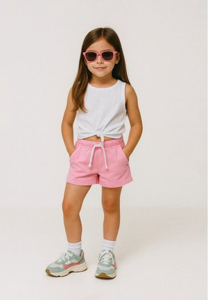 Bílé tílko bez rukávů s uzlovým detaily, růžové šortky s tkaničkou, bílé ponožky a zeleno-růžové tenisky. Dítě má na sobě růžové sluneční brýle.