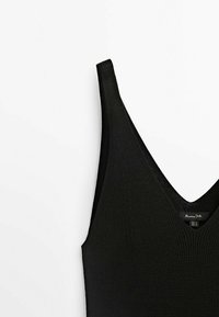 Schwarzes, geripptes Trägertop mit tiefem V-Ausschnitt und dünnen Trägern. Das Material scheint weich zu sein und hat eine subtile Textur; das Markenlabel ist am Ausschnitt sichtbar.