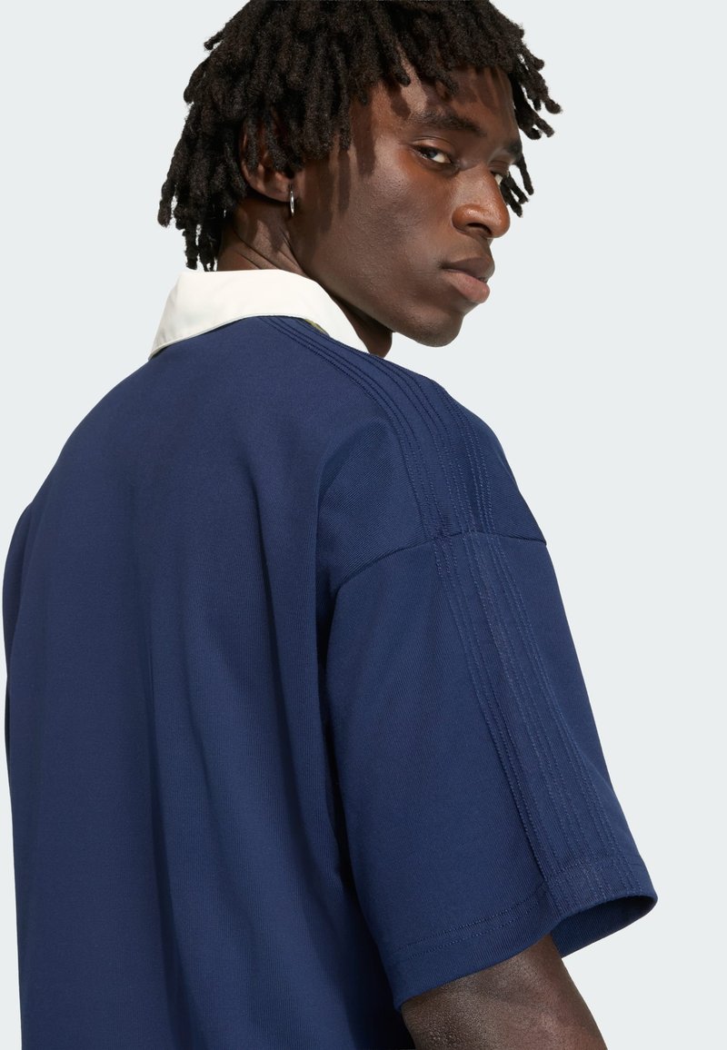 Navy blue sports shirt with a white collar, featuring short sleeves, textured seams, and a relaxed fit, viewed from the back.