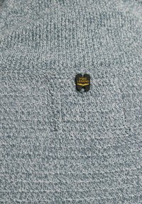 Blauwe gebreide trui met een gestructureerde weefpatroon, een patchzak en een zwart label met "PME Legend" in gouden letters.