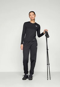 Black long-sleeve top and matching pants made of lightweight fabric, with logo accents and a fitted design. Includes trekking poles.