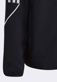 Zwarte sportjack met een gladde textuur, strakke mouwen en karakteristieke witte accenten langs de naden en logodetails.