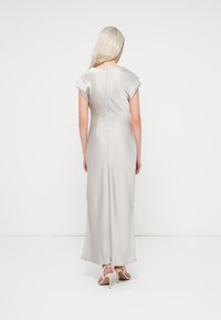 Robe longue, gris clair, avec de courtes manches à capuche, une silhouette droite et une fermeture éclair au dos. Texture lisse et sans motifs visibles.