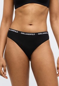 Čierne bavlnené bikiny so širokým elastickým pásom s bielym logom "KARL LAGERFELD". Hladká textúra, klasický strih.