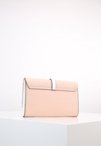 Brzoskwiniowa skórzana kopertówka o zdefiniowanym kształcie, metaliczne srebrne akcenty i białe przeszycia; posiada zapięcie na klapę.