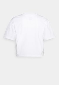 Kortärmad, cropped vit t-shirt i bomull. Har rak skärning och en minimalistisk design med en mjuk textur. Inga grafiska mönster eller tryck.