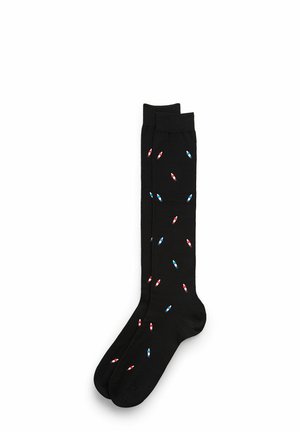 Black knee-high socks with small red and blue bottle patterns. Smooth texture and form-fitting design for comfort and style.