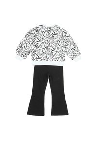 Tenue pour enfant comprenant un haut blanc à manches longues orné de contours de cœurs noirs et un pantalon évasé noir uni.